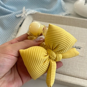 Détail d'un chouchou noeud jaune tricoté avec des perles ambrées sur un plateau