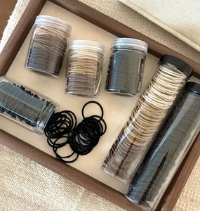 Assorted elastic hair ties in Morandi earth tones stored in transparent jars