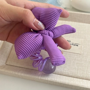 Détail d'un chouchou violet avec nœud, fil de téléphone spirale et perle décorative