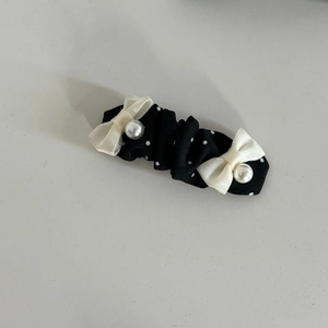 Elegant black polka dot hair clip with white bows and pearl center for hair styling