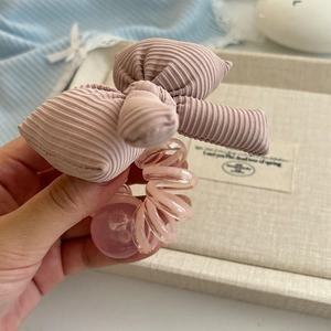 Vue détaillée d'un chouchou rose avec nœud, texture spirale et perle décorative