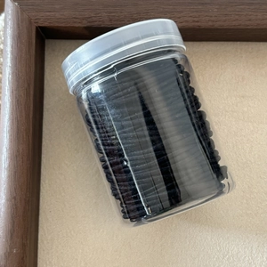 Detail of high elasticity seamless black hair ties stored in a clear plastic jar with lid