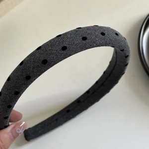 Dettaglio del cerchietto in tessuto grigio a pois neri che mostra la texture morbida