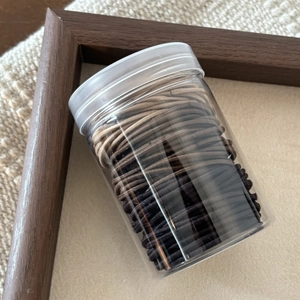 Jar of durable seamless hair ties in coffee and black tones for daily hair styling