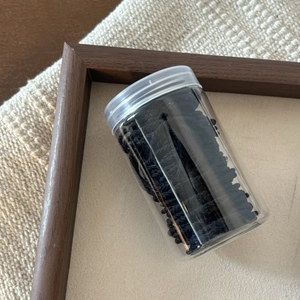 Detail shot of durable black elastic hair bands stored in a clear cylindrical bottle
