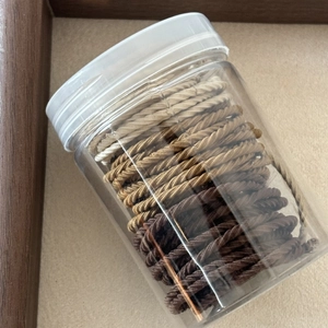 Neutral earth tones spiral elastic hair ties set in a clear plastic storage jar