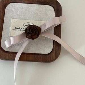 Elegant brown fabric rose hair clip with pale pink silk ribbon in a wooden box