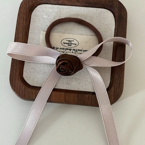 Detail of a brown handmade fabric rose and ribbon bow on an elastic hair tie