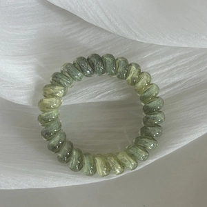 Spiral telephone wire hair tie with green and gray marble gradient pattern on white fabric