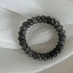 Detail of spiral hair tie with grey marble texture on white silk fabric background