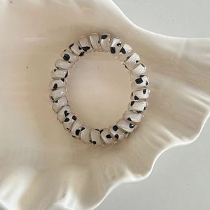 Détail d'un élastique spirale à motif vache posé dans un plateau décoratif blanc