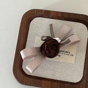 Detailed close-up of brown rose hair bow featuring a heart rhinestone and satin textures
