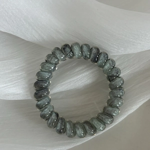 Close-up of spiral telephone wire hair tie with grey marble pattern on white tulle