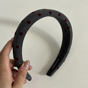 Close-up of handmade sponge headband with grey knitted fabric and red polka dots