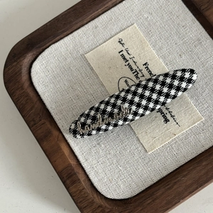 Classic black and white houndstooth hair clip with a silver handmade metal tag