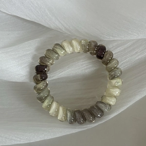Close-up of multicolored spiral phone cord hair ties in earthy tones on soft tulle