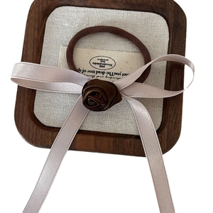 Elegant brown rose hair scrunchie with ribbons on a wooden display tray