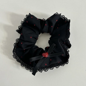 Close-up of black polka dot hair scrunchie with lace trim and red heart bow detail