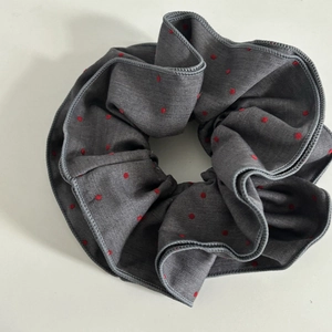 Detailed close-up of grey satin scrunchie with red polka dots and fine stitching