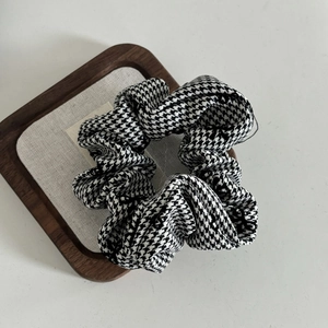 Close-up of fluffy black and white houndstooth check fabric scrunchie on a white tray