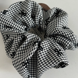 Close-up of houndstooth hair scrunchie with delicate bow prints and soft fabric pleats