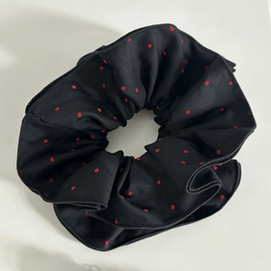 Detail of oversized black satin scrunchie with classic red polka dots and elastic band
