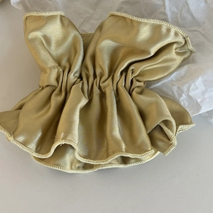Gros plan d'un chouchou en satin or champagne avec design plissé élastique et texture douce