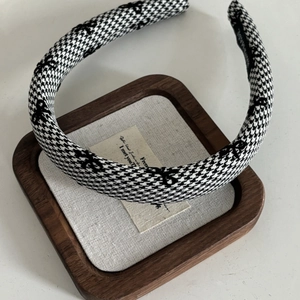 Classic houndstooth fabric headband with black bow embroidery on a textured wooden tray