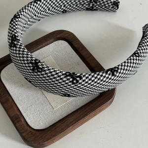 Detail of houndstooth headband with black bow embroidery on a wooden tray