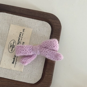 Detailed macro view of a purple knitted bow hair clip featuring soft textured yarn weaving