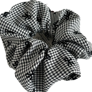 Black and white houndstooth hair scrunchie with small bow patterns and pleated fabric