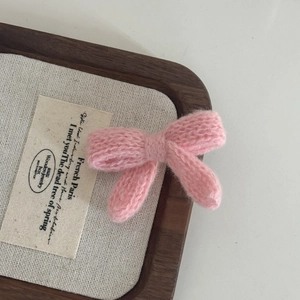 Close-up of pink knitted bow hair clip featuring detailed handmade crochet texture