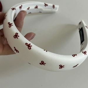 Thick padded headband in white fabric with burgundy bow patterns and soft sponge fill