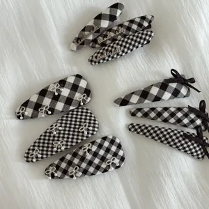 Detail of British style checkered hair clips with handmade metal tags and pearl bows