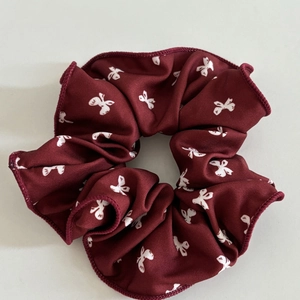 Detailed texture of burgundy scrunchie with white butterfly patterns and sewn edges