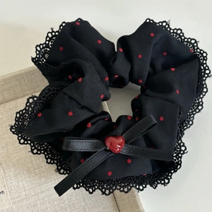 Detail of black polka dot scrunchie with lace trim and red heart charm accent