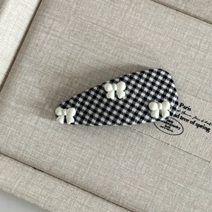 British style black and white houndstooth hair clip with three white bows on a tray