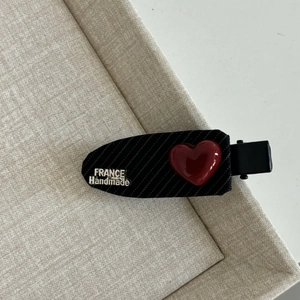 Detail of red heart duckbill hair clip with black stripes and France Handmade text