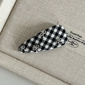 Detail of British plaid BB hair clip with silver metal bows and pearl accents