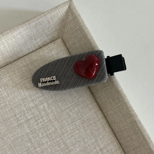 Detail of a handmade hair clip with grey denim fabric and a glossy red heart