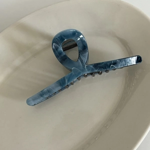 Detail of grey ink wash acetic acid hair claw clip with marble texture on white tray