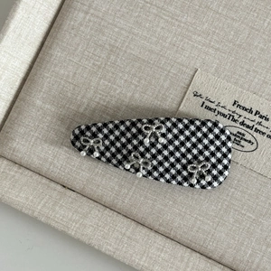 Detail of British style houndstooth hair clip with silver bows and faux pearls