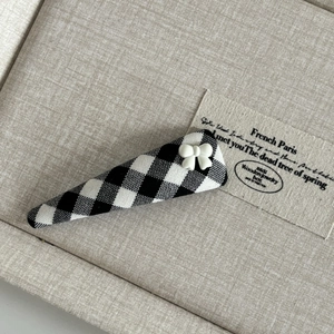 Detailed macro view of black and white checkered fabric hair clip with resin bow decoration