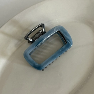 Detail view of rectangular blue marble acetate hair claw clip with white ink smoke pattern