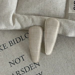 Close-up of beige fabric wrapped BB hair clips with textured woven finish for kids