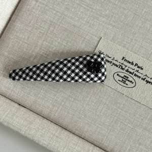 Close-up of British style houndstooth hair clip with a black bow on beige fabric