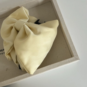 Detailed view of elegant cream satin double-layered bow hair claw clip with glossy finish