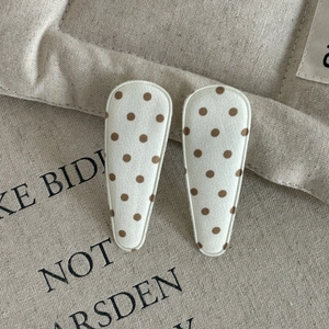 Handmade brown polka dot fabric drop hair clips on textured linen background