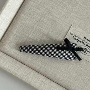 Detail of British style black and white plaid hair clip with a delicate black silk bow