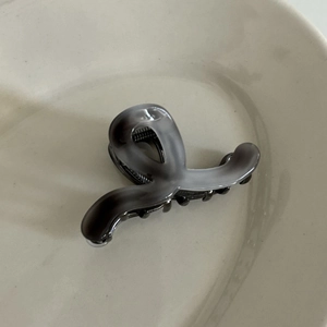 Detailed view of the gray ink texture on the acetic acid hair claw clip in a ceramic tray